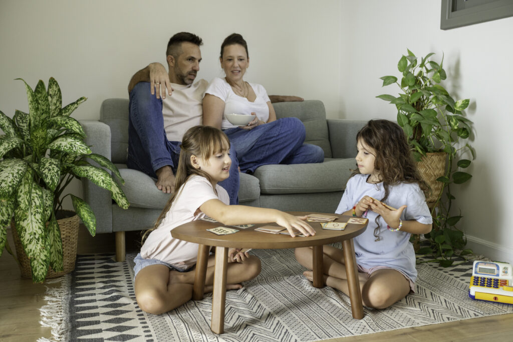 משפחה יושבת יחד בסלון, ילדות משחקות